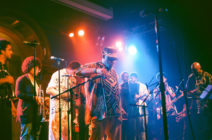 Members of Pan Afrikan Peoples Arkestra stand on stage under stage lights at the Lodge Room in Highland Park.